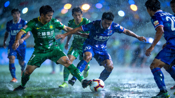 中超联赛，北京国安对阵上海申花，球员在雨战中奋力拼搏